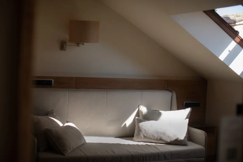 Sunlit daybed with linen pillows, seen through an open attic doorway